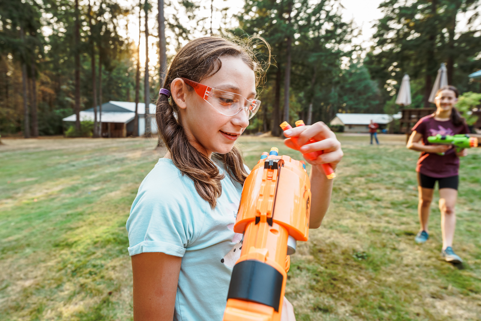 Tween girls having playful nerf gun battle outside