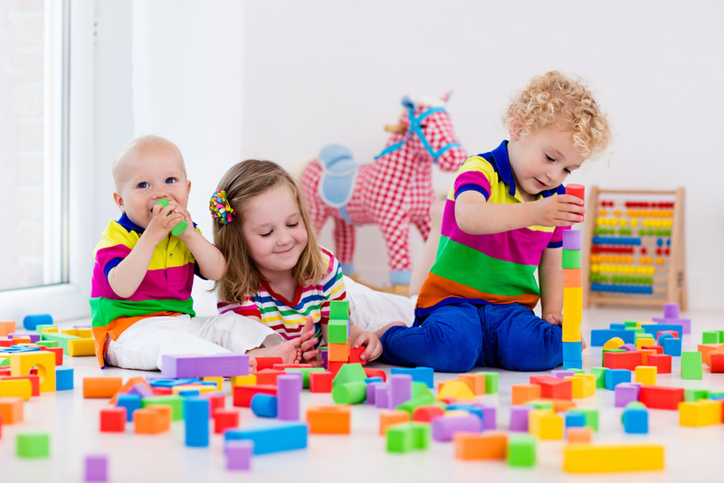 Children playing with colorful toy blocks building block tower